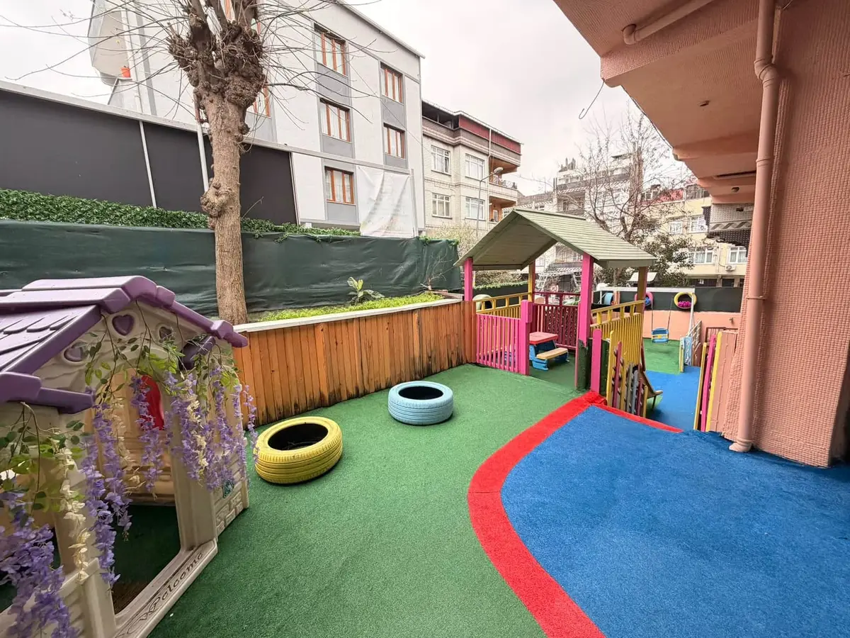 Oyun evi, boyalı lastikler ve yeşil-mavi zeminiyle okul bahçesi