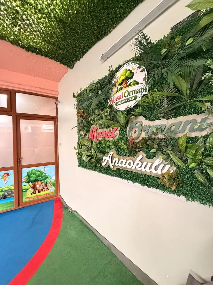 Masal Ormanı Anaokulu logosu ve yeşil bitki duvarıyla süslenmiş okul girişi